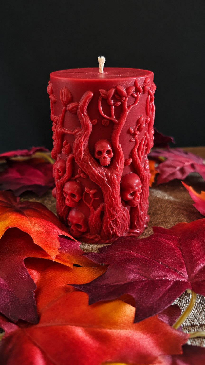 Back of the red Bonekeeper candle showing skulls nestled within sculpted tree branches.