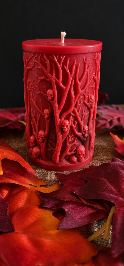 Back of the red Grovekeeper candle showing bare branches and small sculpted skulls.